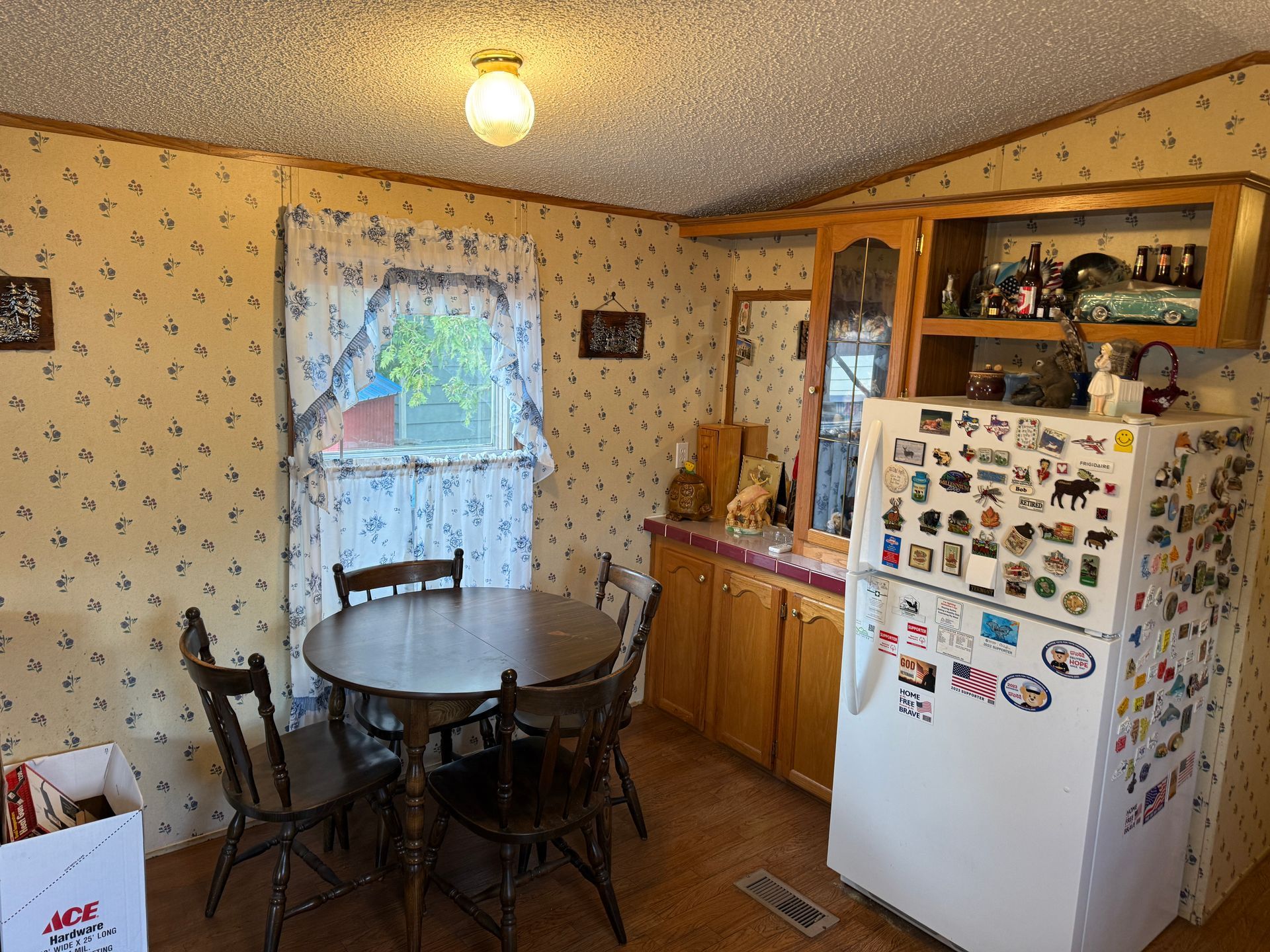 Small kitchen with round table, wooden cabinets, and a white fridge covered in magnets.
