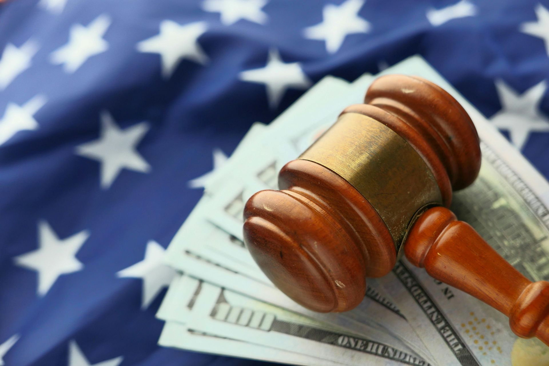 Gavel on U.S. dollar bills over a blurred American flag background