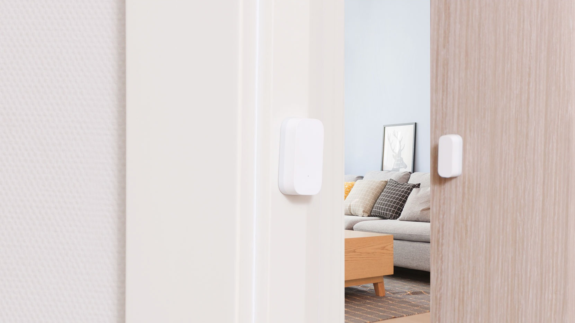Capteur de porte blanc installé sur le cadre de la porte, donnant sur un salon.