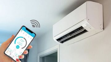 Main utilisant un smartphone pour régler la température d'un climatiseur intelligent. Unité blanche sur un mur blanc.