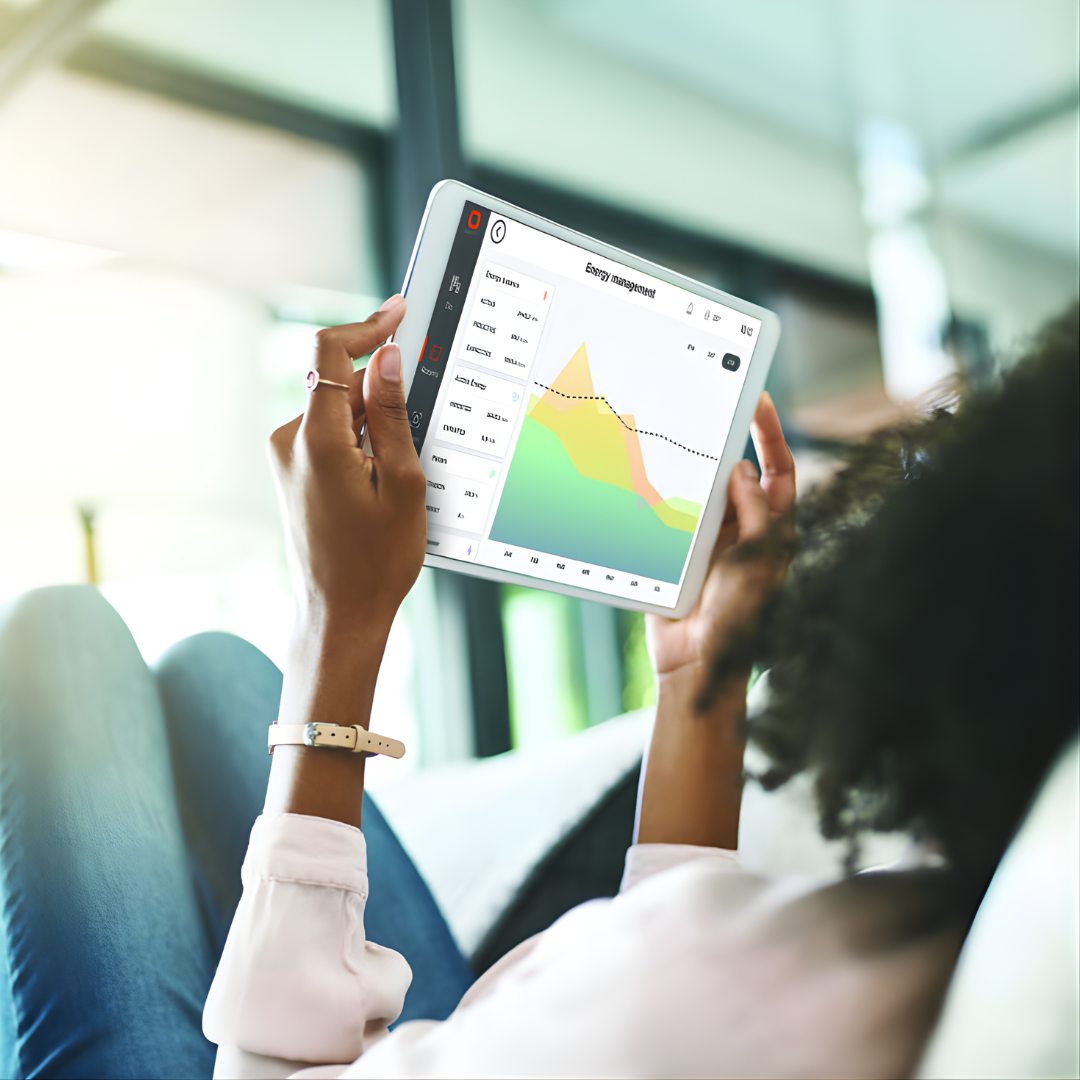 Une femme utilise une tablette pour consulter un graphique de données tout en se relaxant à l'intérieur.