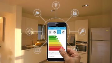 Main tenant un téléphone affichant des données d'efficacité énergétique, avec des icônes de maison intelligente