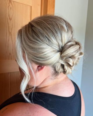 A woman with blonde hair in a bun is wearing a black tank top.