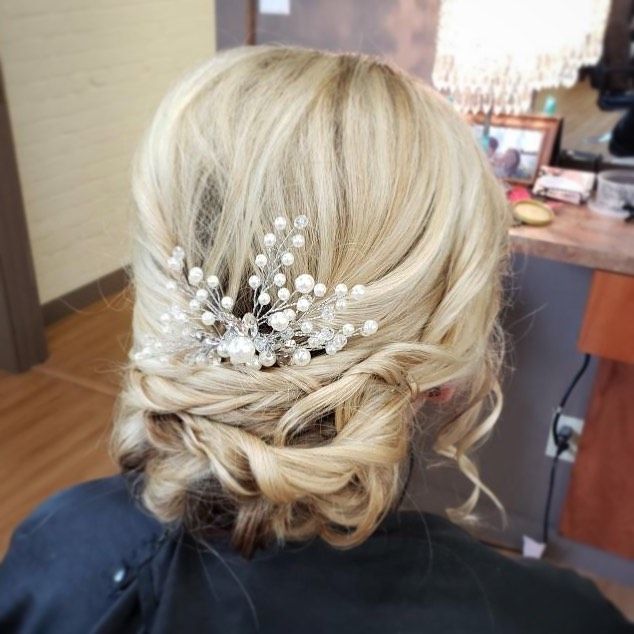 A woman with blonde hair is wearing a bun with pearls in it.