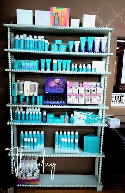 Shelves displaying various teal skincare products and boxes, with a promotional poster in the center.