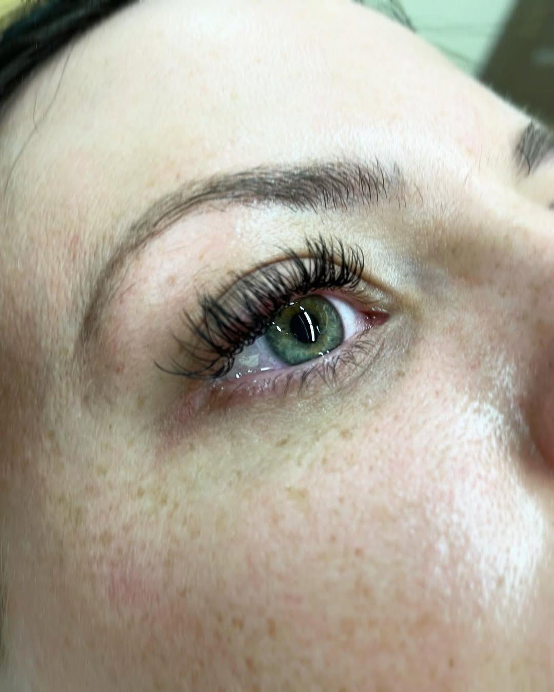 A close up of a woman 's eye with long eyelashes and freckles.