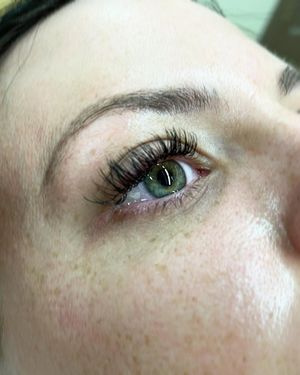 A close up of a woman 's eye with long eyelashes and freckles.