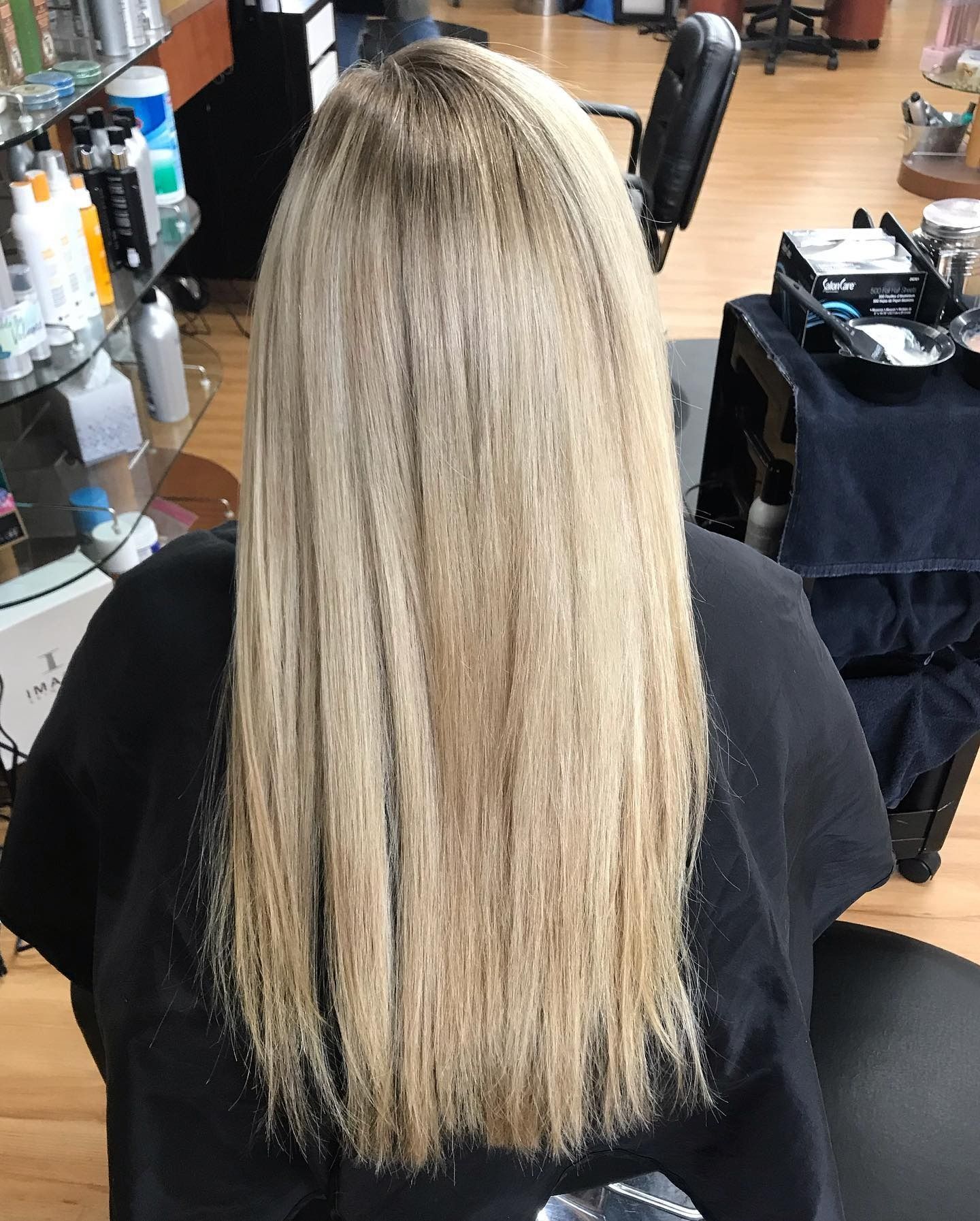 A woman with long blonde hair is sitting in a chair in a salon.