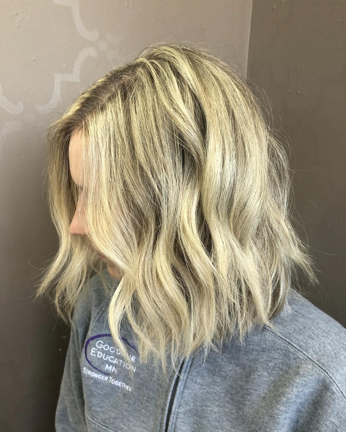 A woman with blonde hair is wearing a gray sweatshirt.