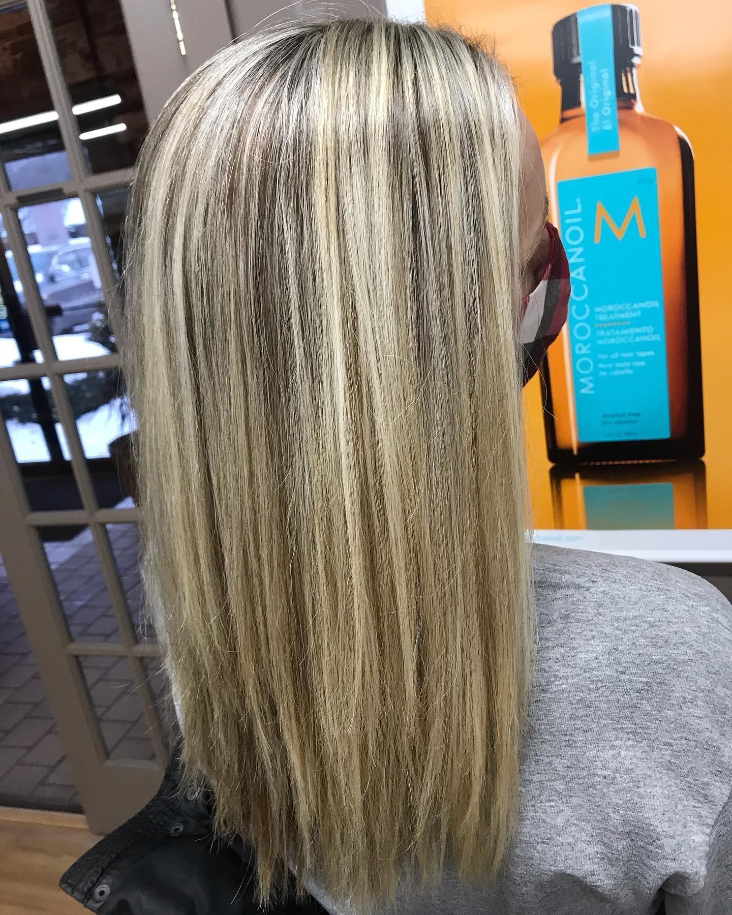 A woman is sitting in front of a bottle of moroccan oil