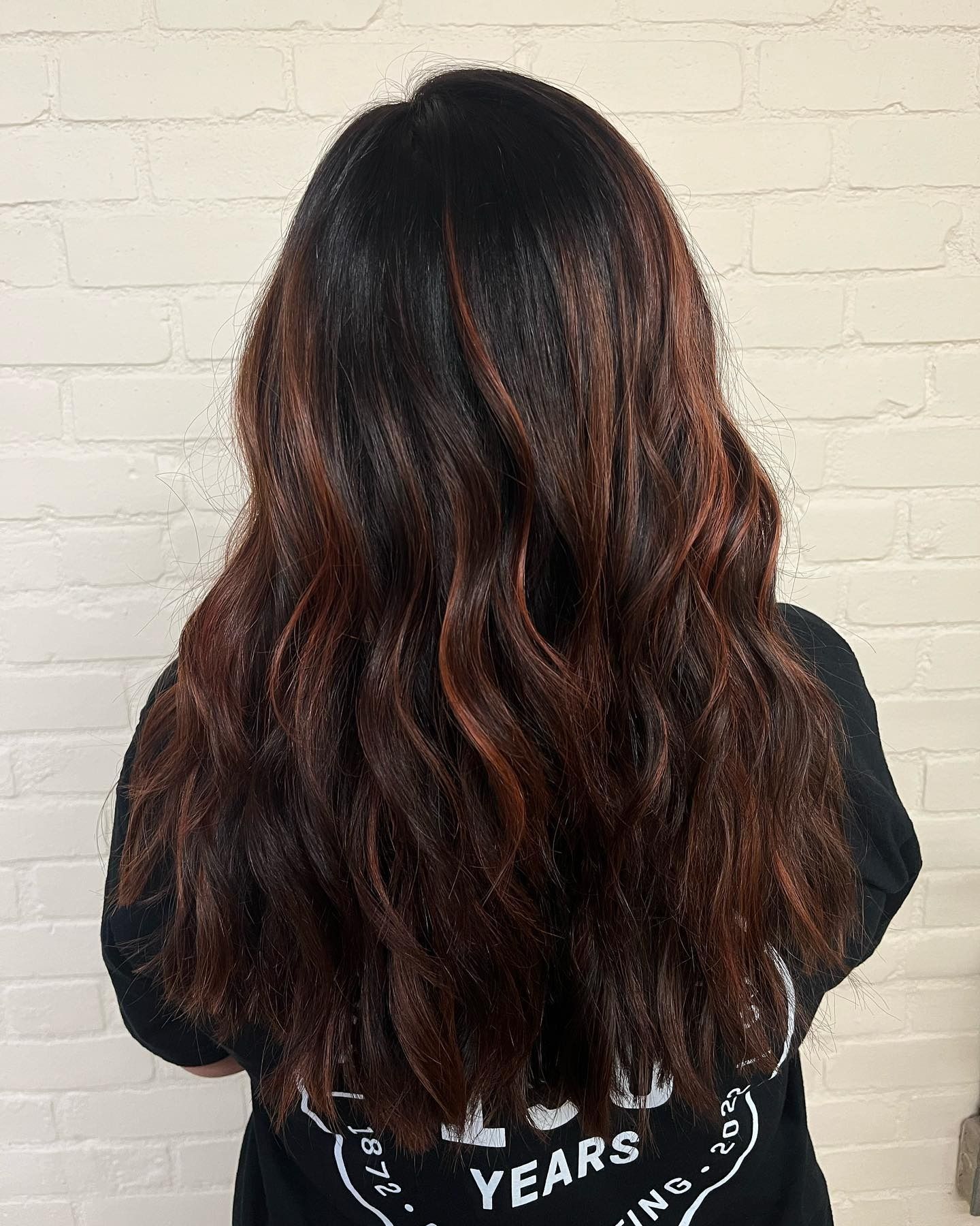 A woman with long dark hair is wearing a black shirt.