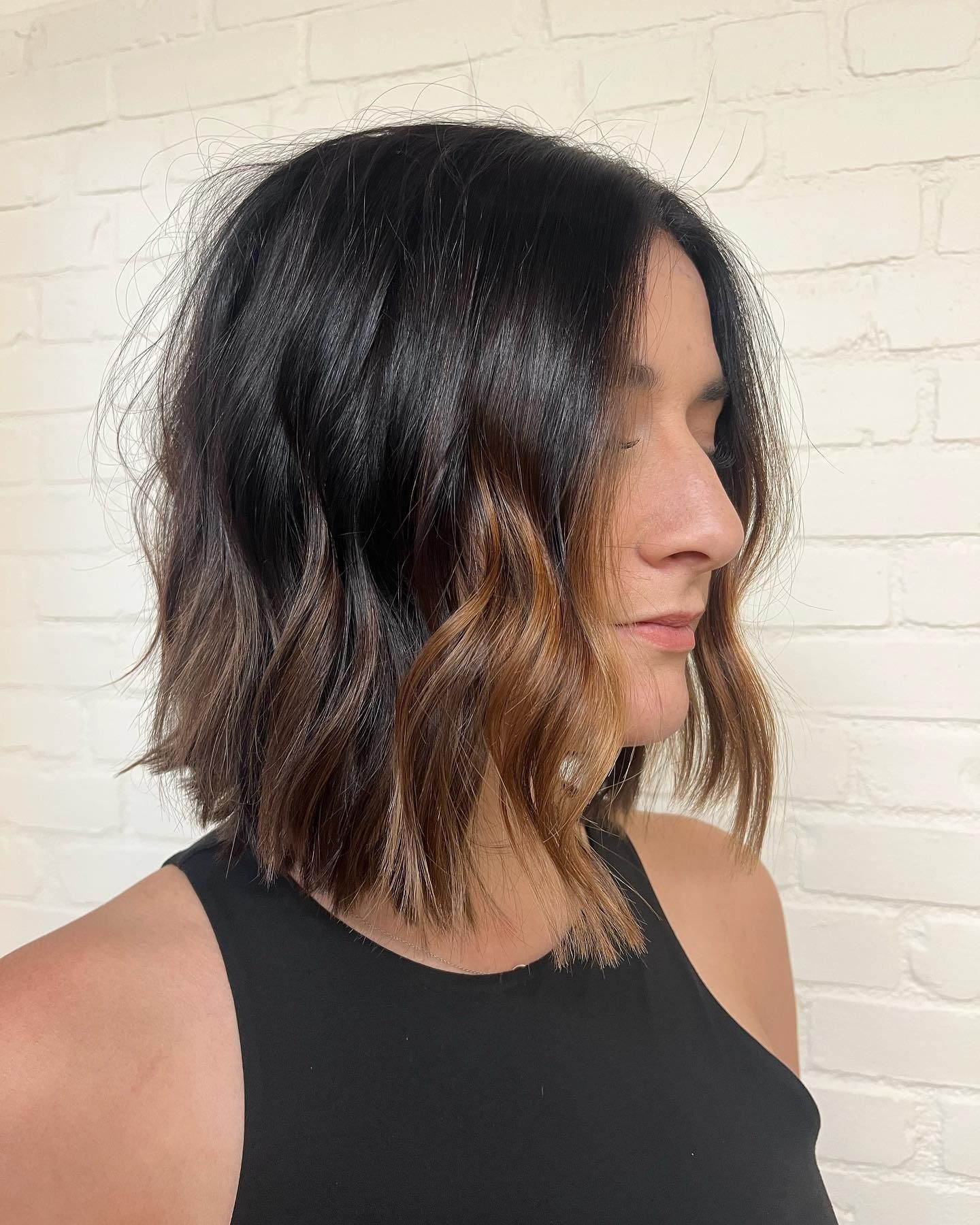 A woman with short black hair is wearing a black tank top.