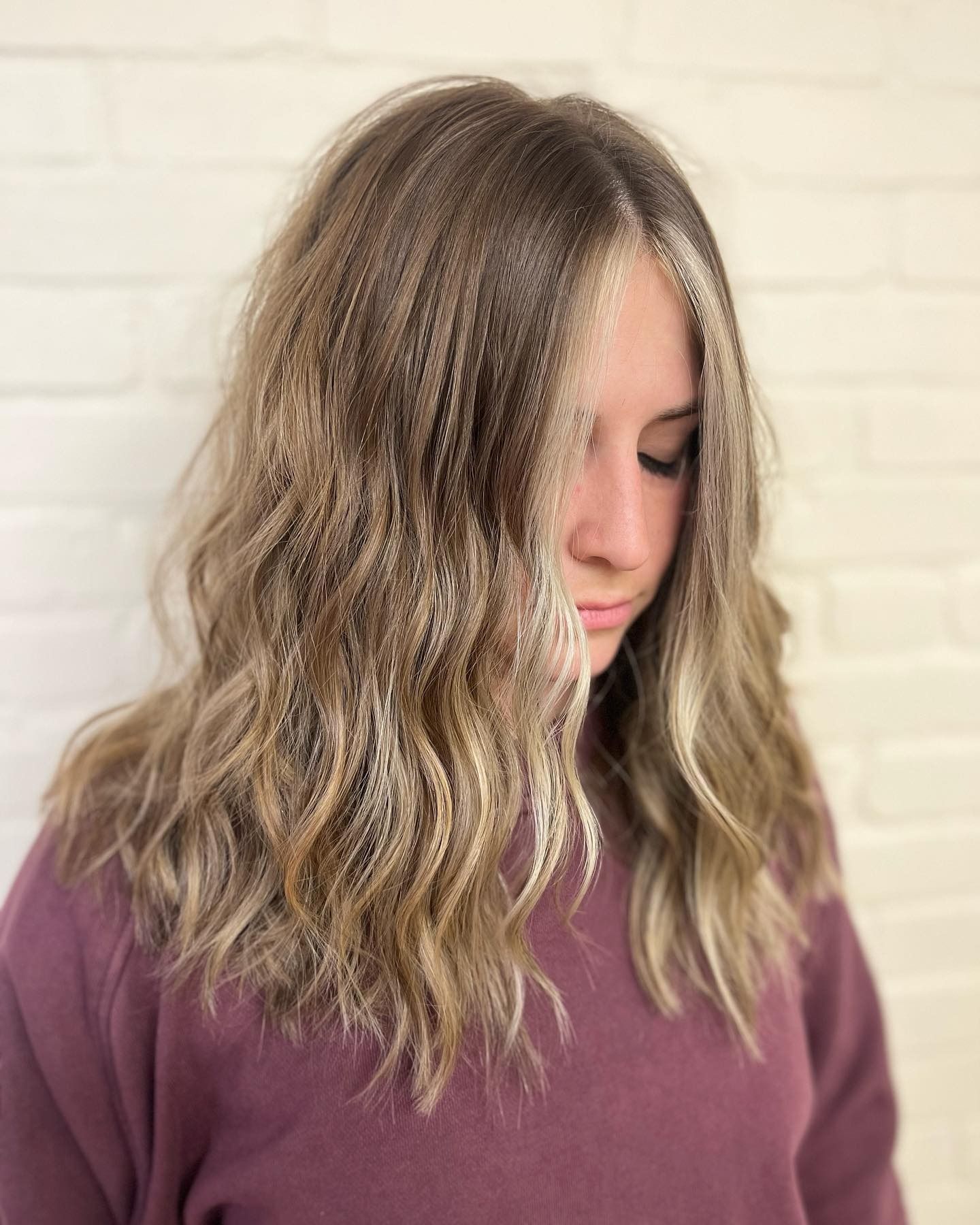 A woman with long blonde hair is wearing a purple sweater.