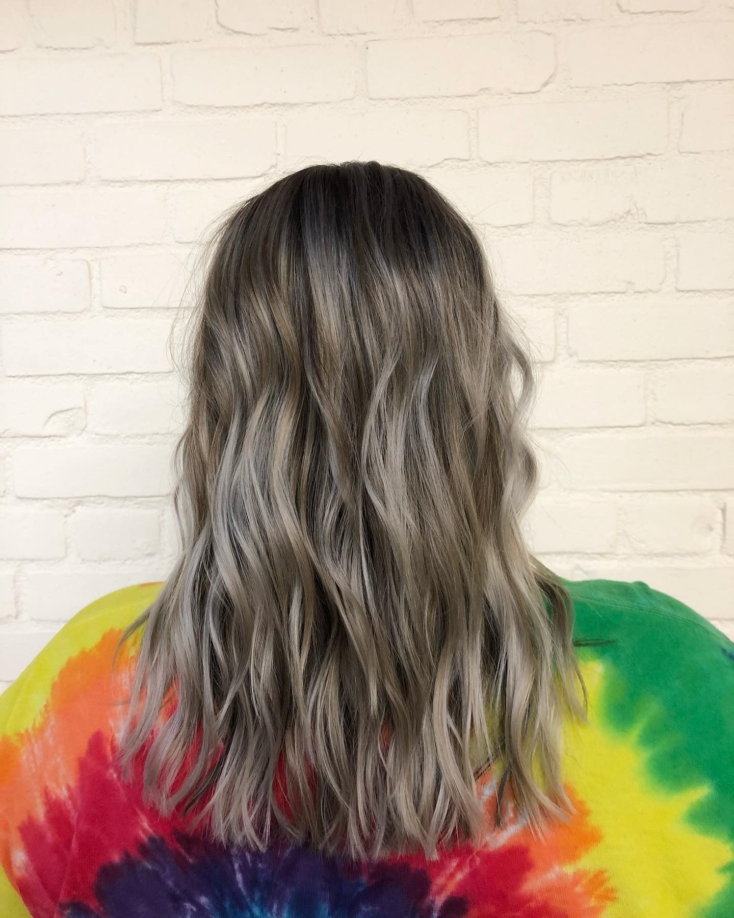 A woman with long hair is wearing a tie dye shirt.