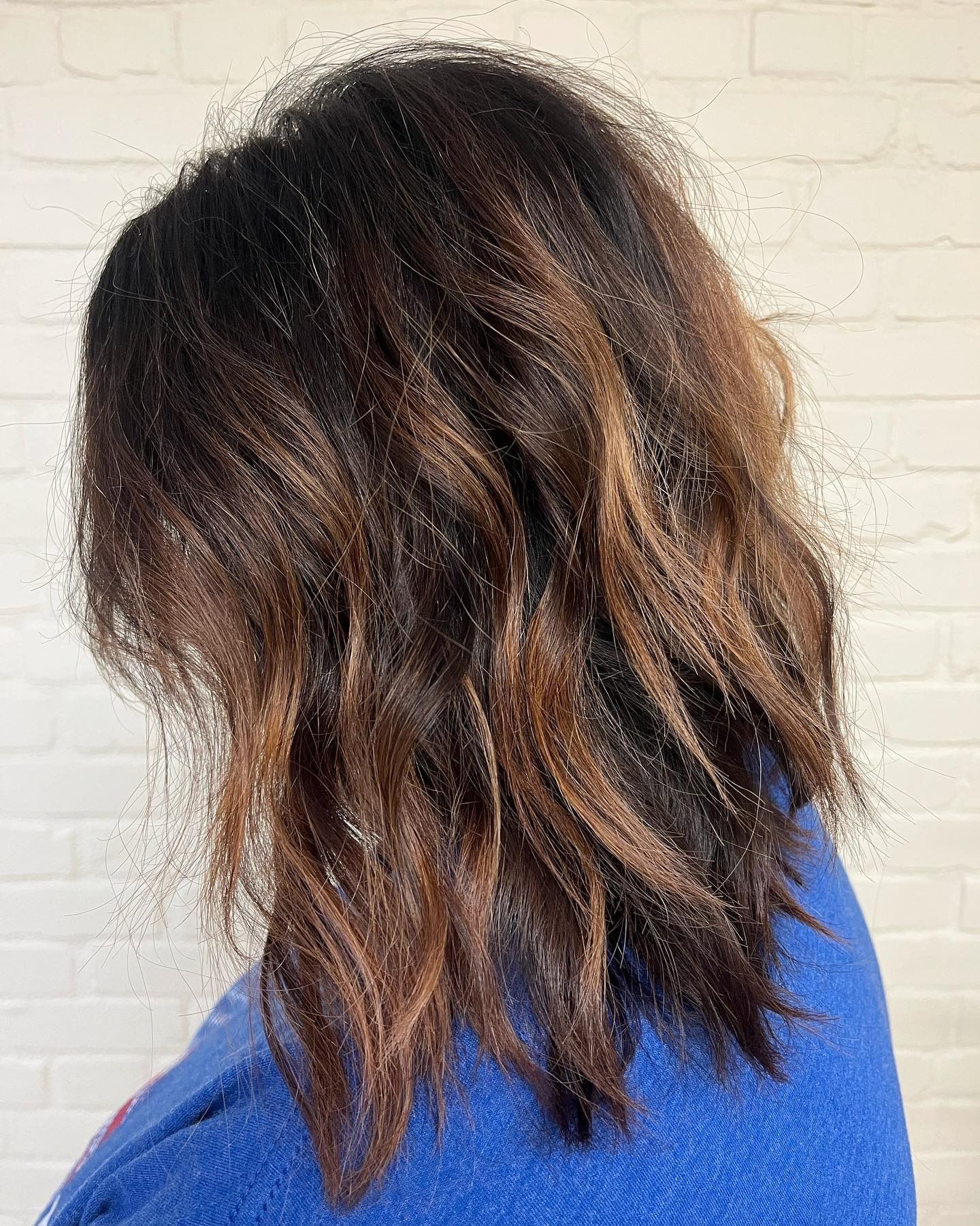 A woman with long brown hair is wearing a blue sweater.