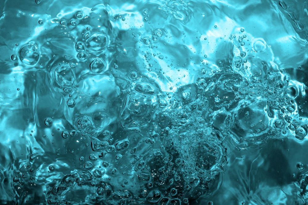 A close up of a blue water surface with bubbles coming out of it.