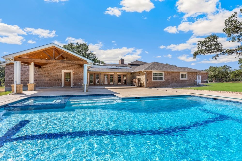 There is a large swimming pool in front of a house.