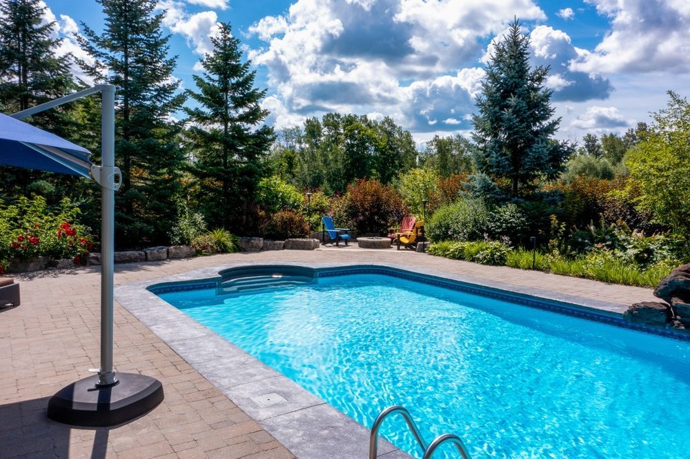 There is a large swimming pool in the backyard with a blue umbrella.