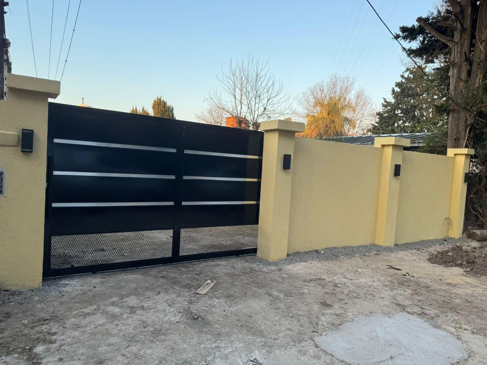 Puerta negra y pared amarilla, camino de grava, durante el día.