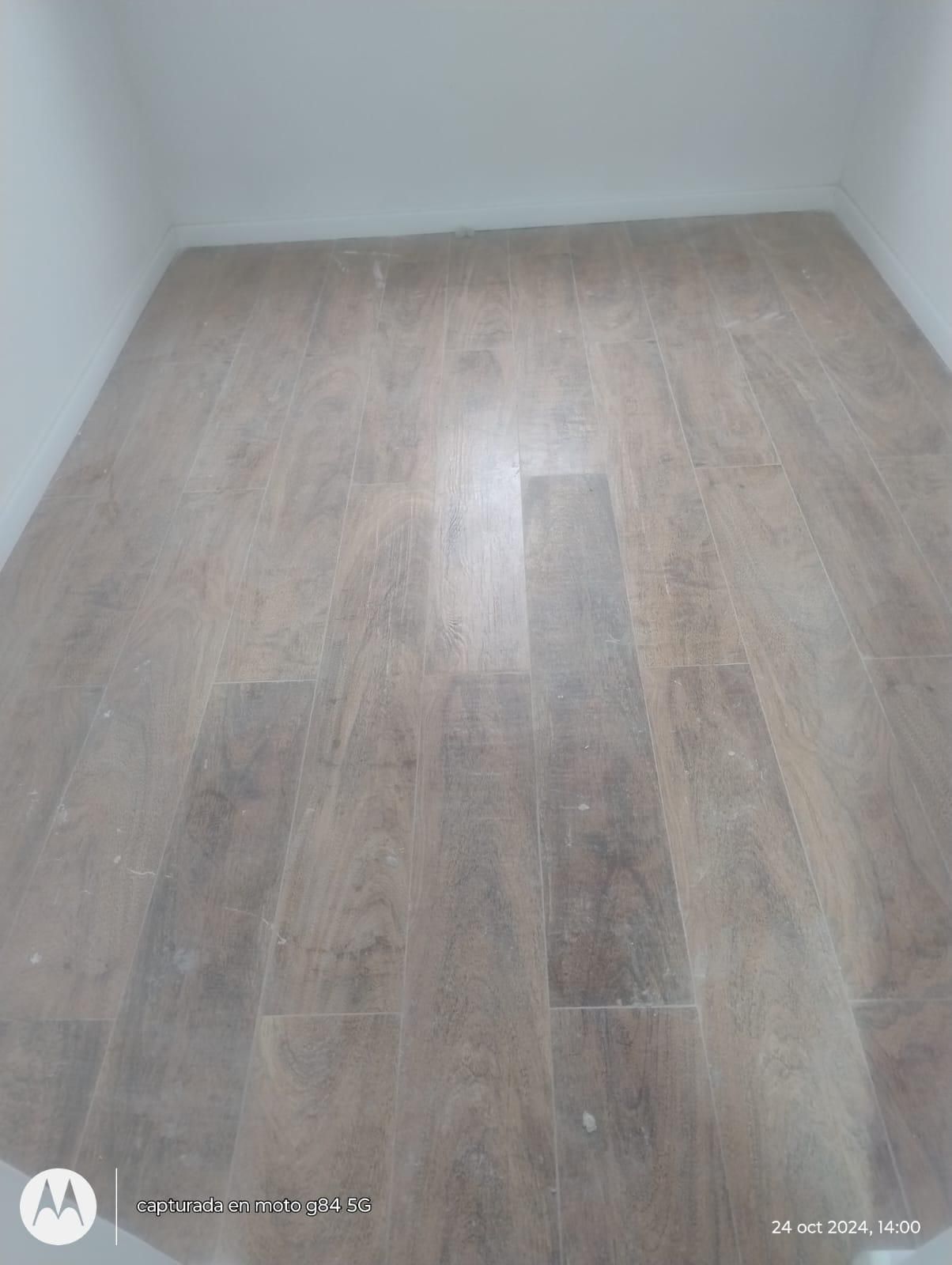 Suelo de imitación madera de color marrón claro en una habitación pequeña con paredes blancas.