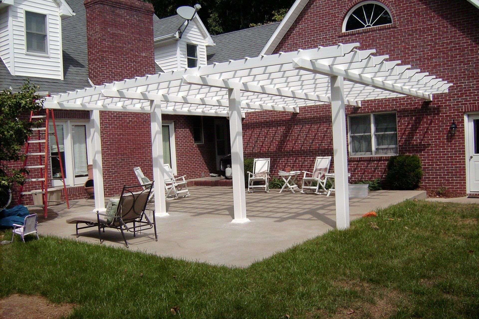 A brick house with a white pergola in front of it