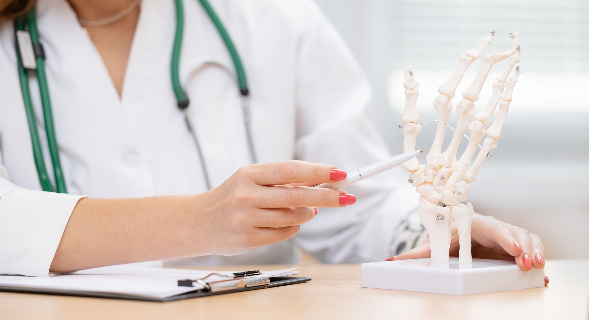 Ein Arzt zeigt auf ein Handskelettmodell und erklärt die Anatomie.