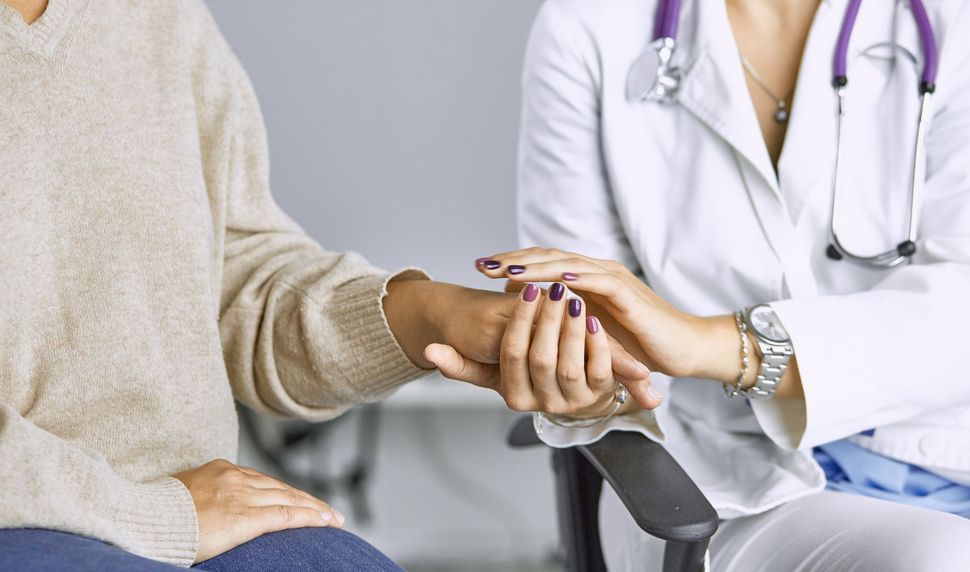 Arzt im weißen Kittel hält das Handgelenk des Patienten und versucht, ihn zu trösten. Lila Stethoskop.