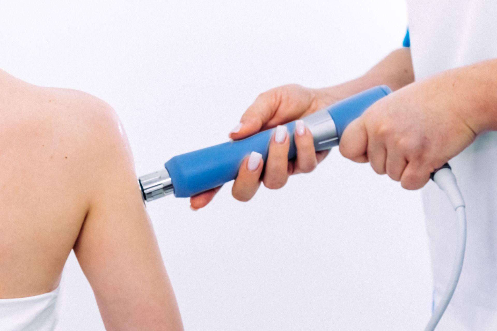 Ein medizinischer Fachmann verwendet ein blaues Gerät an der Schulter eines Patienten.