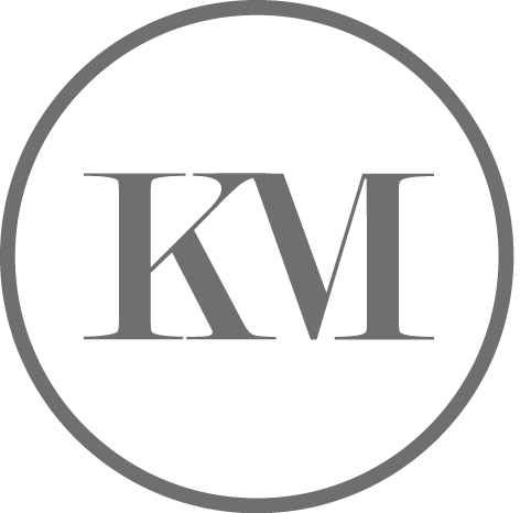 Graue Buchstaben „KM“ in einem grauen Kreis.