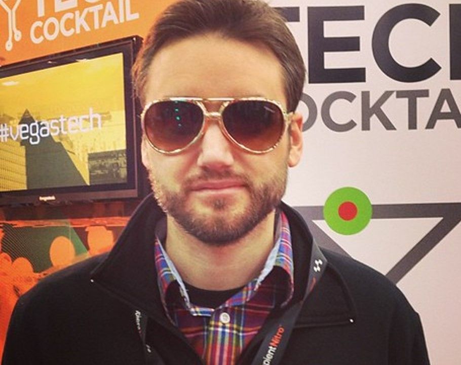 A man wearing sunglasses stands in front of a sign that says cocktail