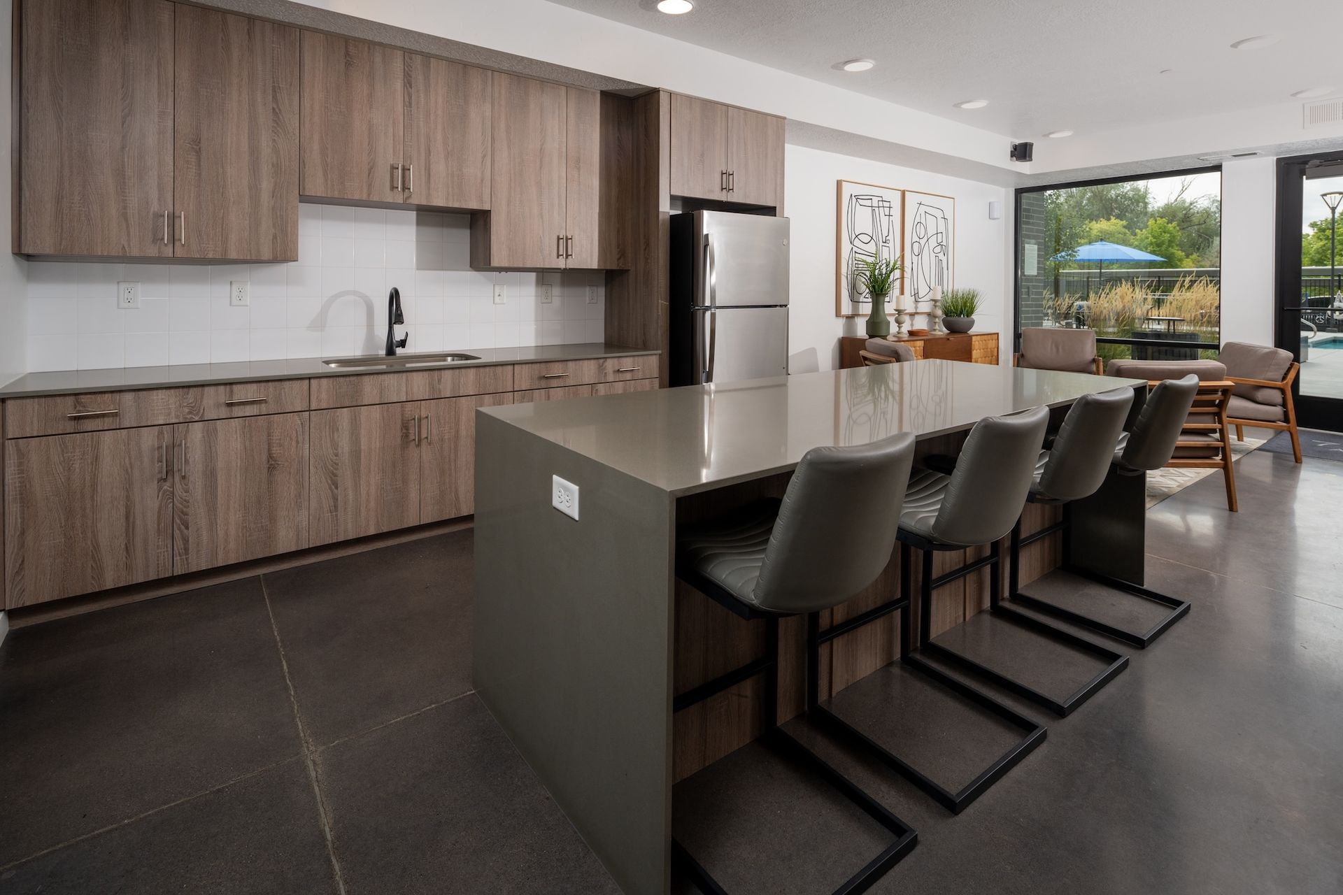 Modern kitchen with wood cabinets, gray island with stools, and stainless steel appliances.
