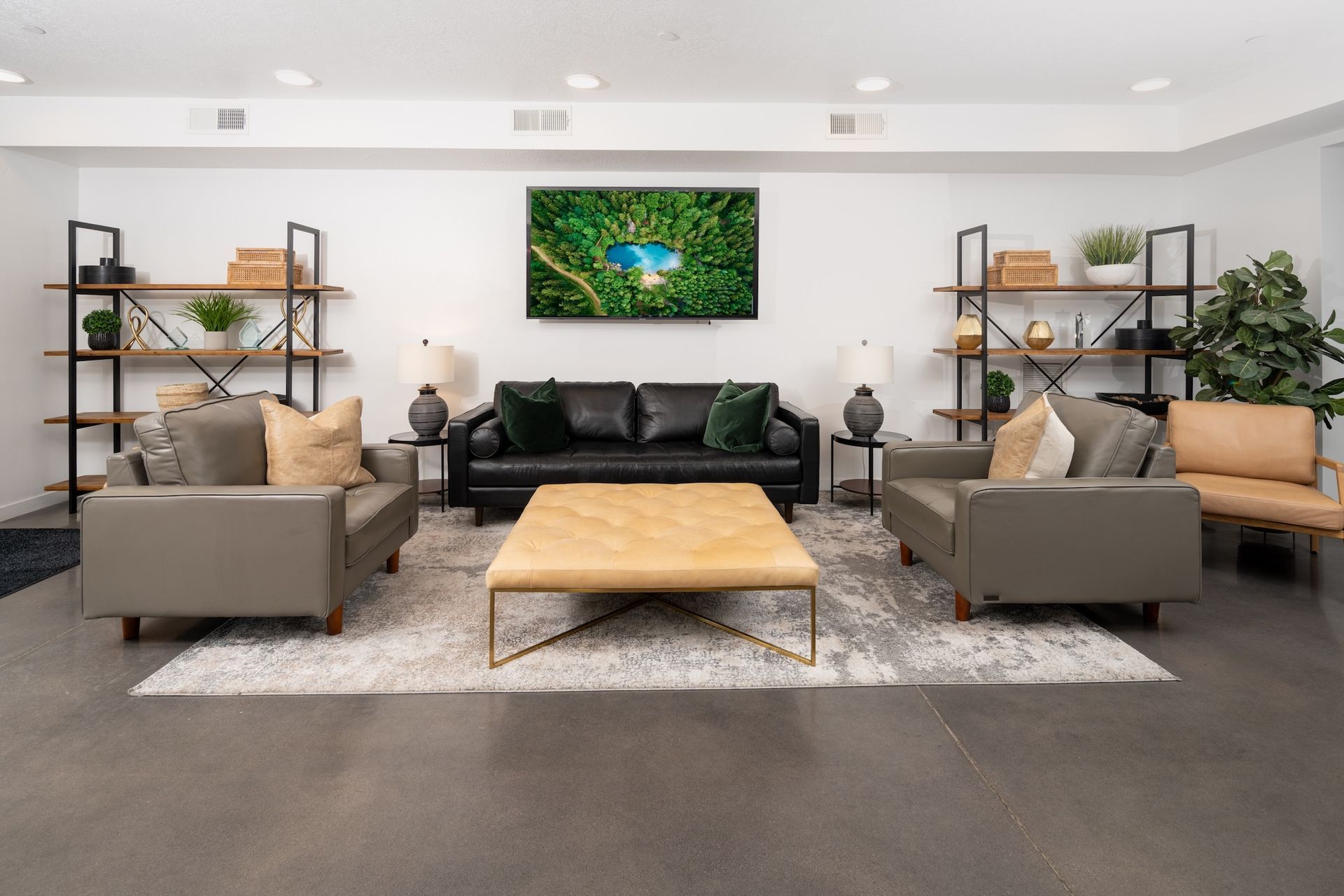 Modern living room with leather furniture, shelves, and a large TV mounted on a white wall.