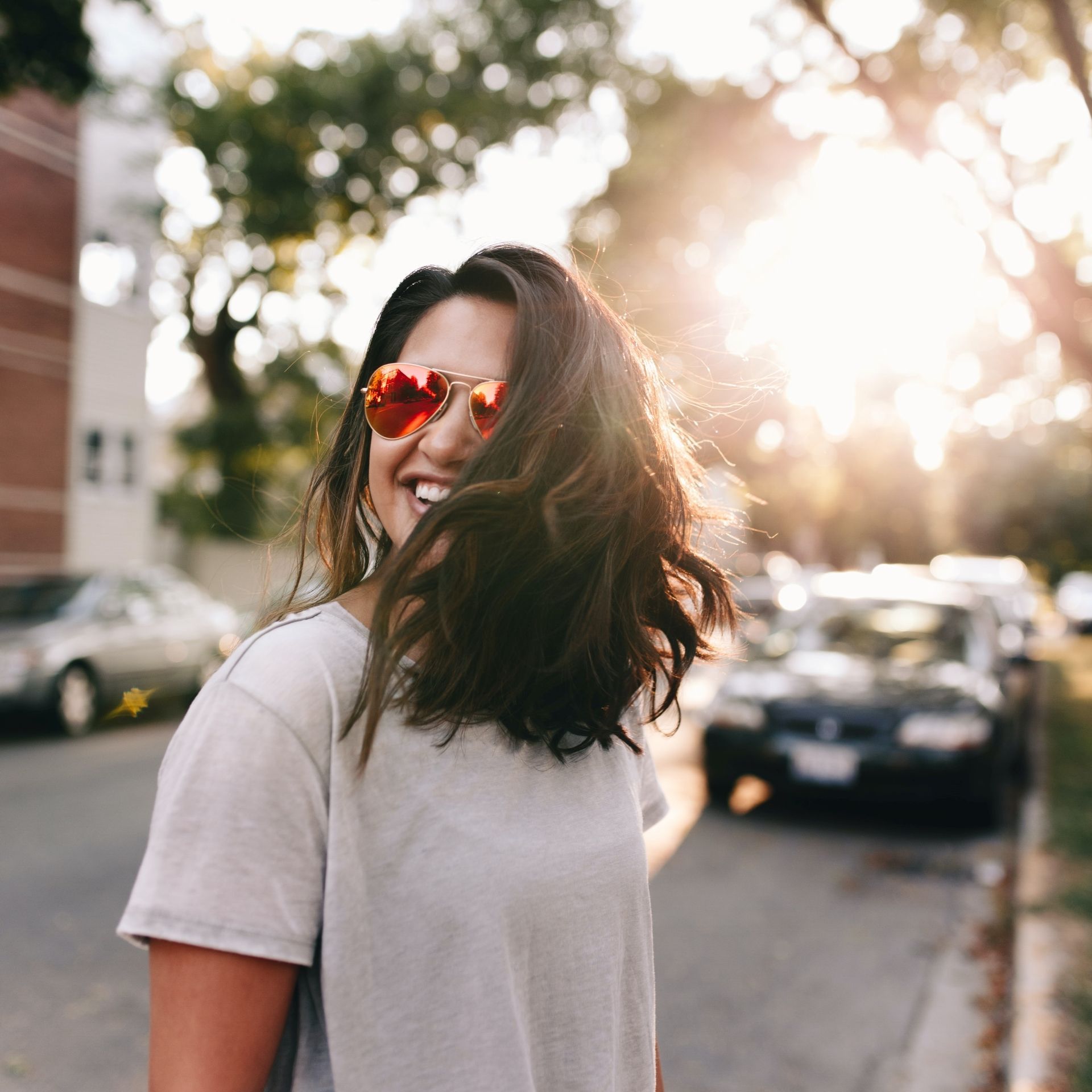 A woman wearing sunglasses is walking down a street.