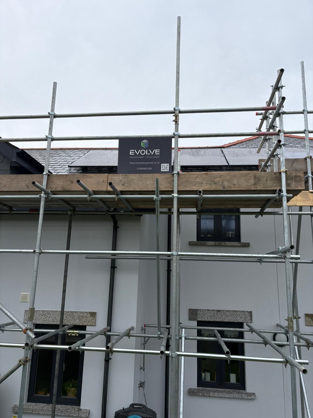 Modern two-story house with brick and white exterior under a blue sky, construction in progress.