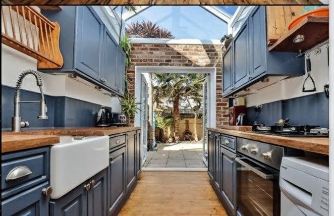 Bright, modern kitchen with white cabinets, gray island, stainless steel appliances, and wooden floors.