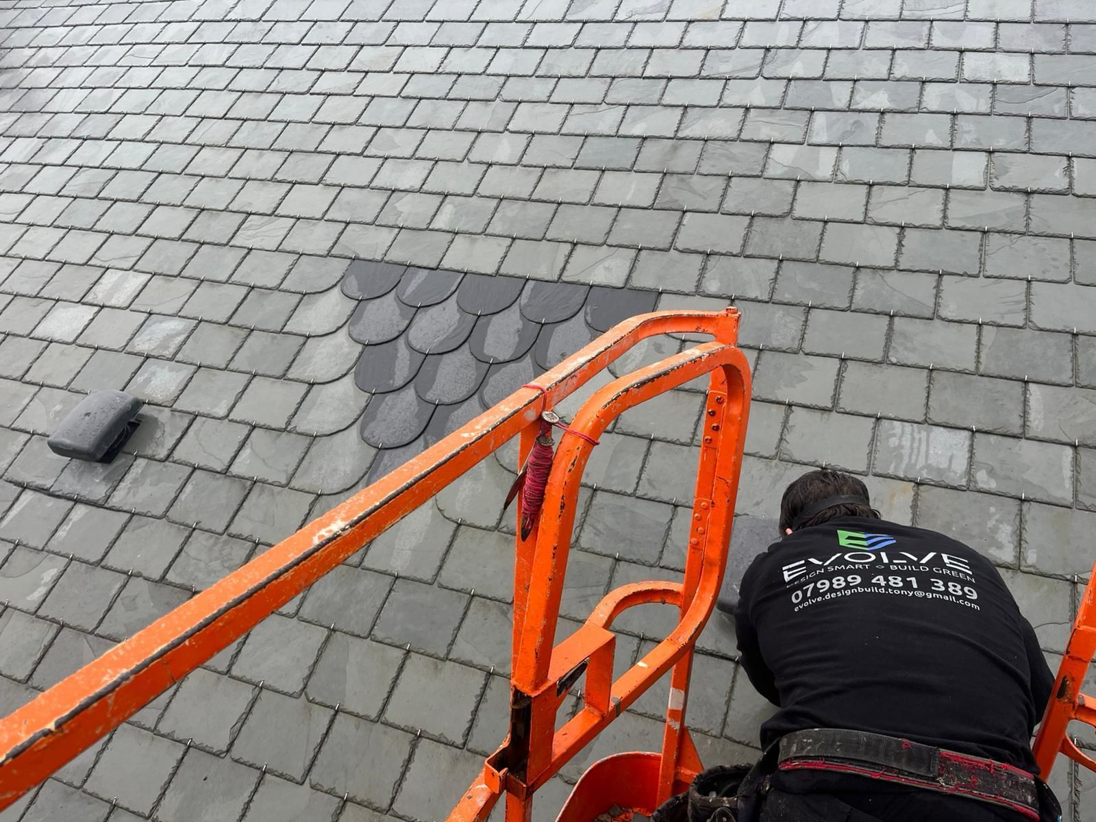 A house with a green roof, solar panels, and a skylight in a residential area.
