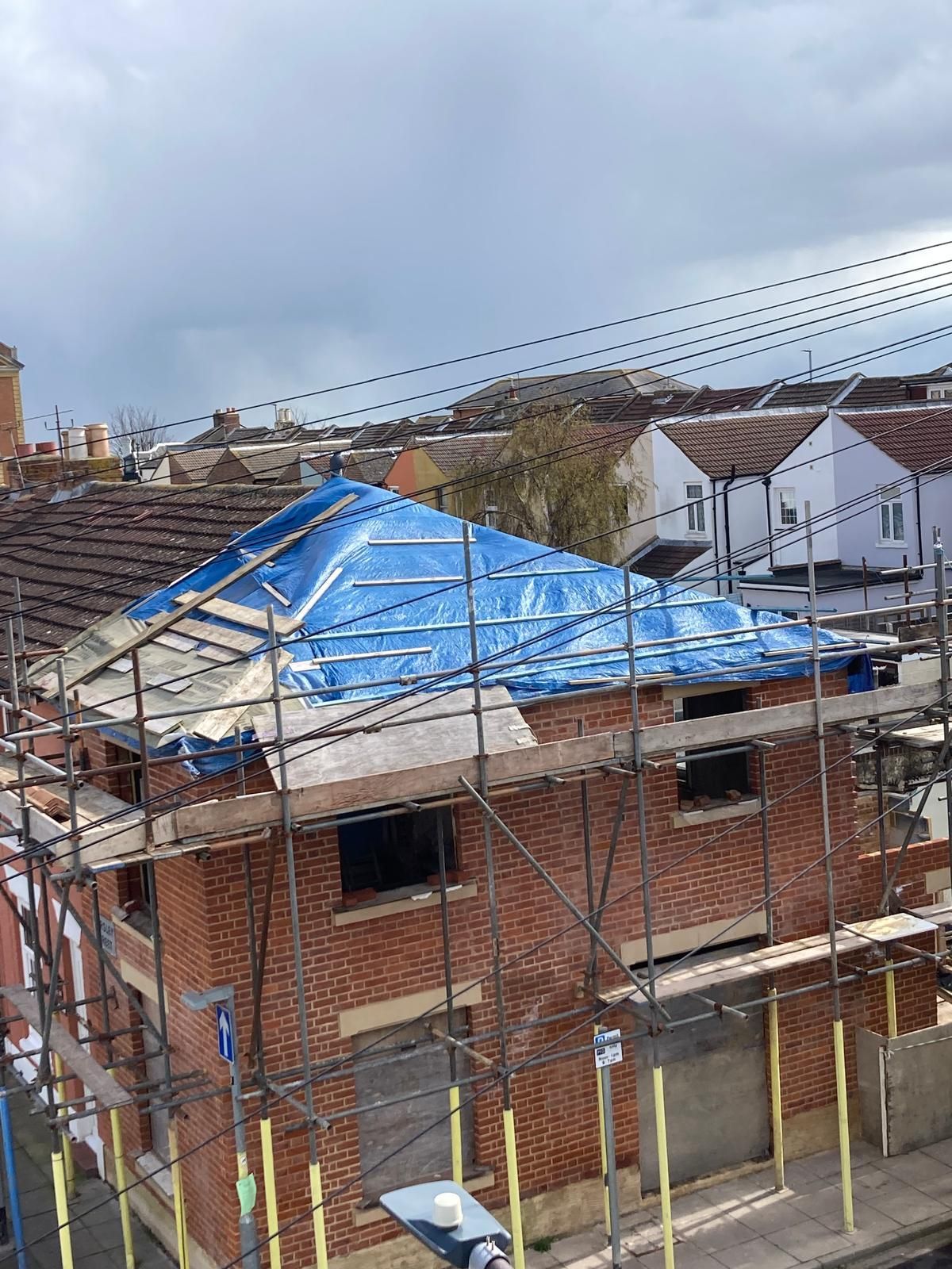 Three roofers installing shingles on a house roof on a sunny day.