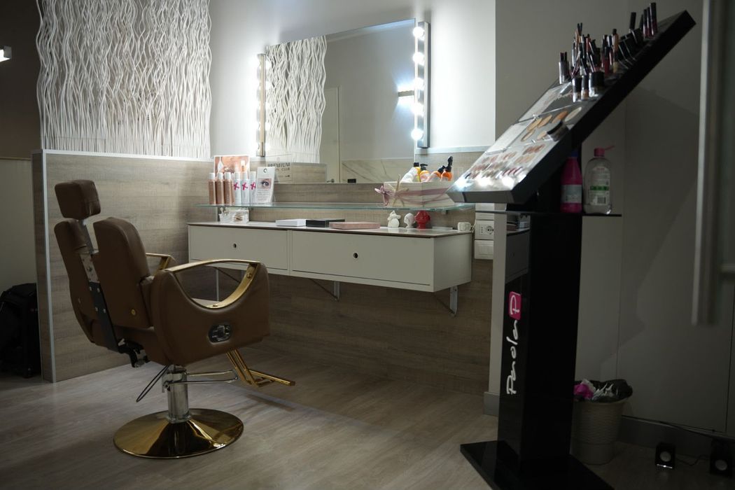 Moderna stanza da trucco con specchi illuminati, postazione trucco e sedie marroni.