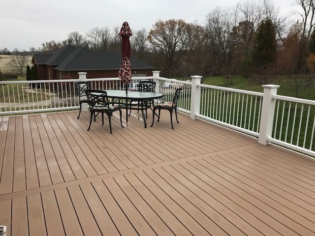 A white cat sits on a gray wooden surface, looking toward the camera with a calm, focused expression.