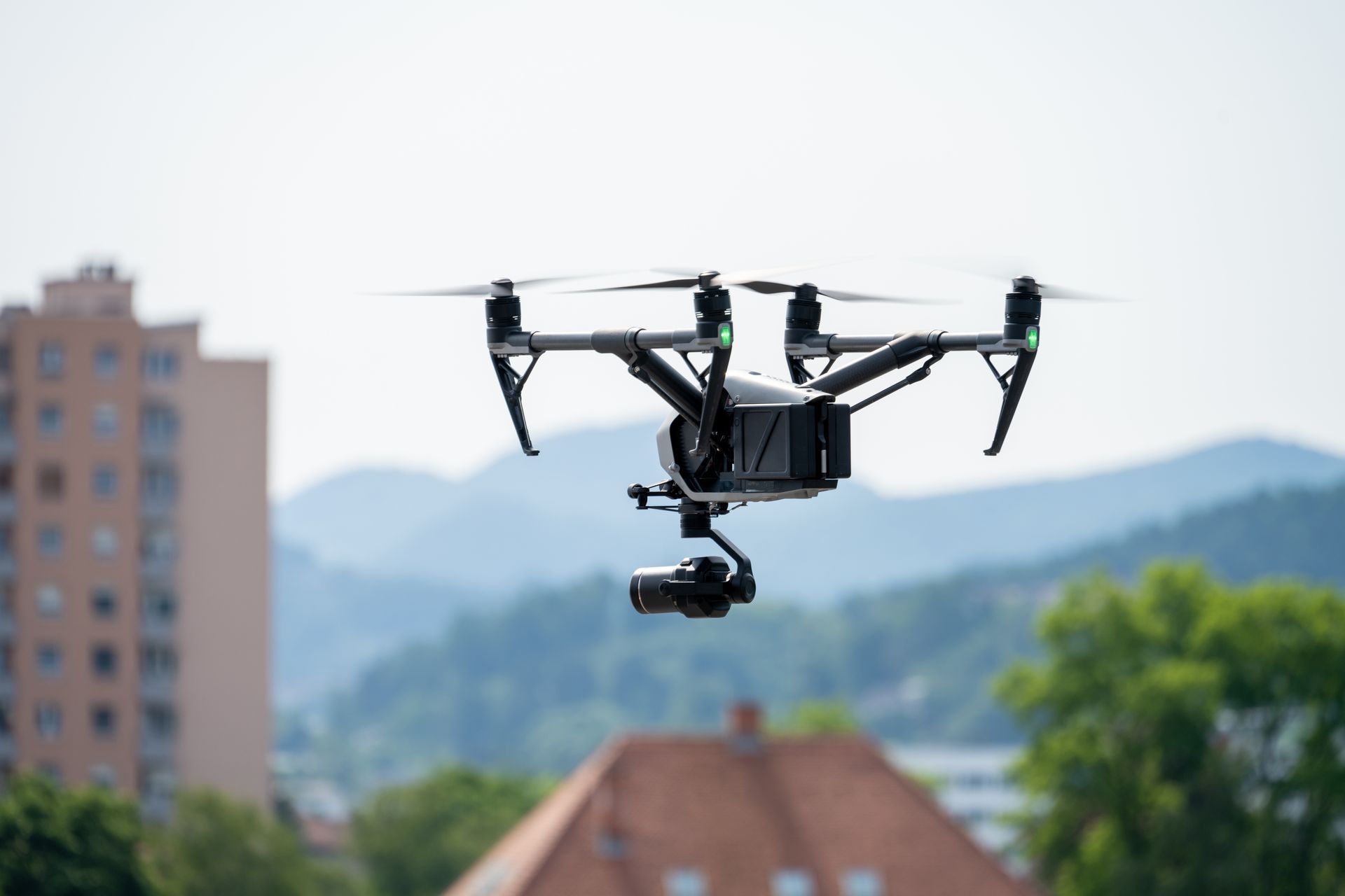 A drone with a camera attached to it is flying over a city.