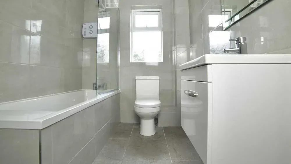 A bathroom with a toilet , sink , bathtub and window.