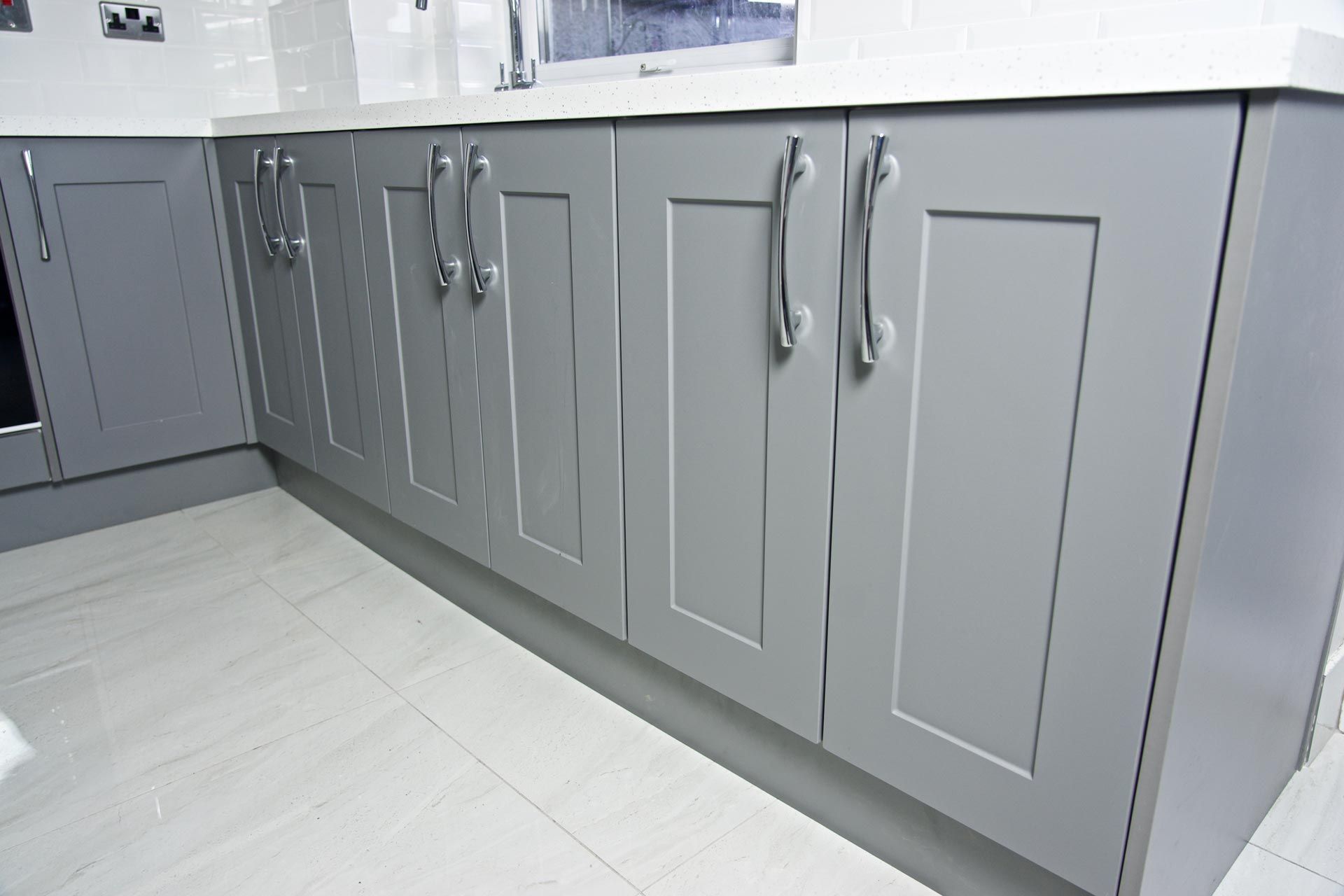 A kitchen with gray cabinets and white counter tops