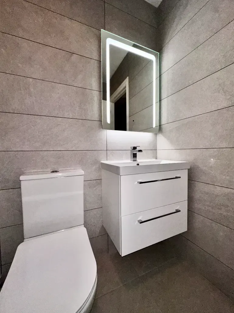A bathroom with a toilet , sink and mirror