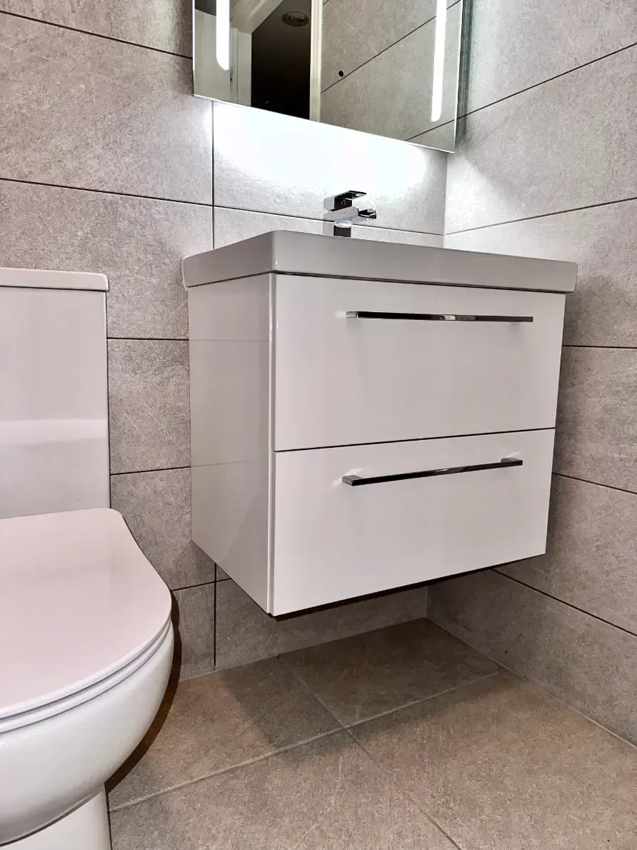 A bathroom with a toilet , sink and mirror.