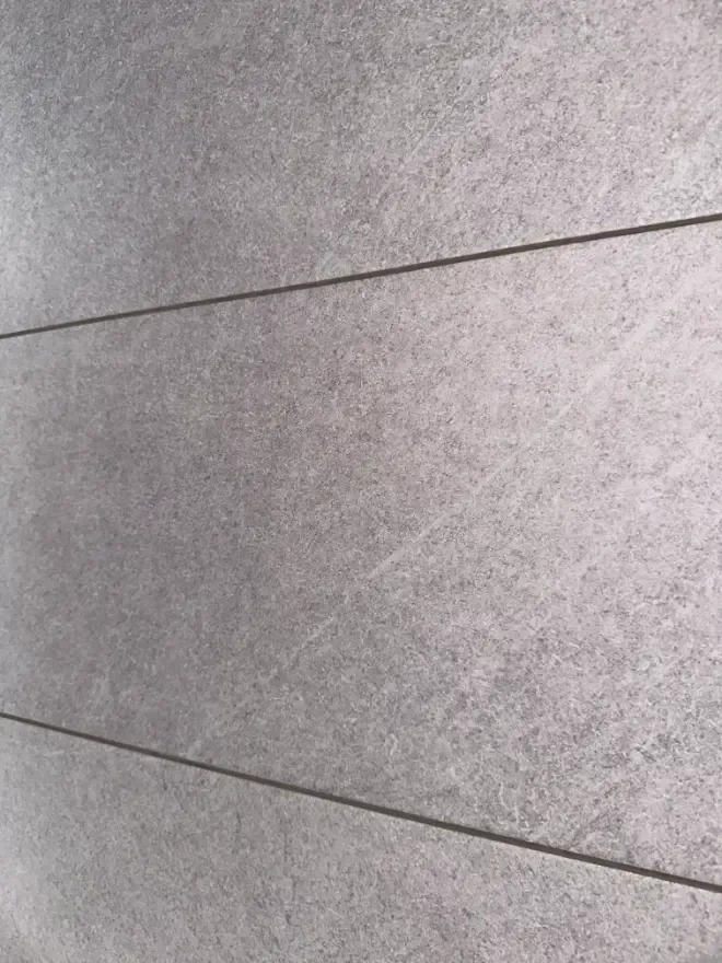 A close up of a gray tile wall.