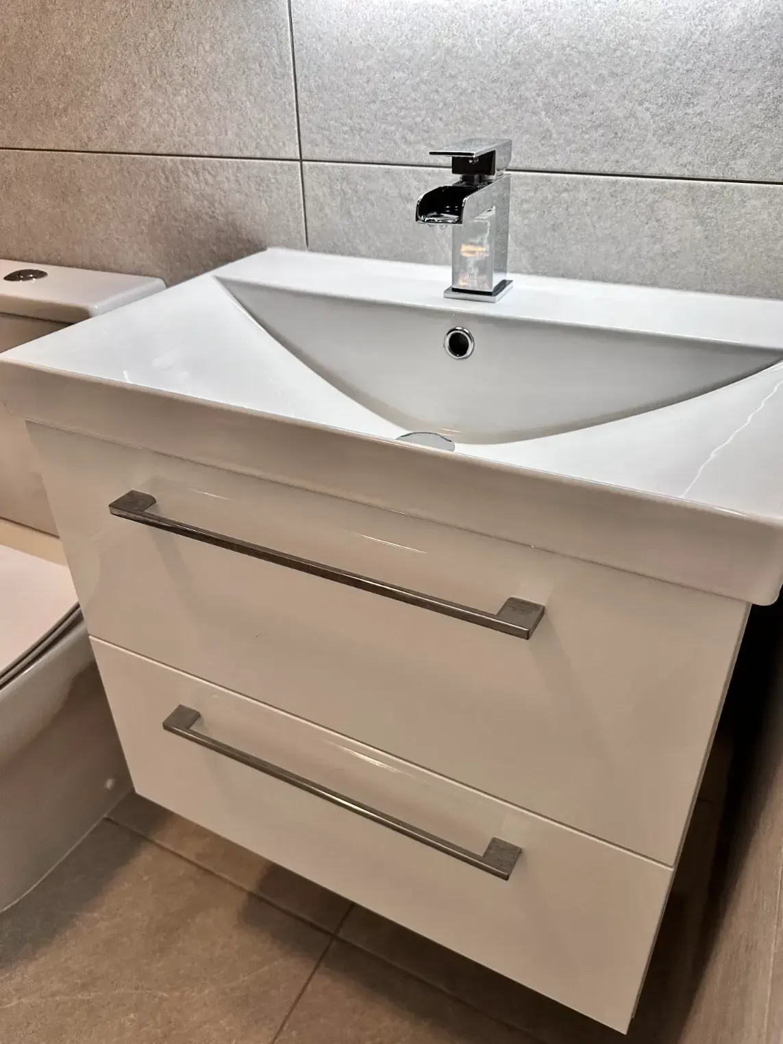 A bathroom sink with two drawers and a toilet.