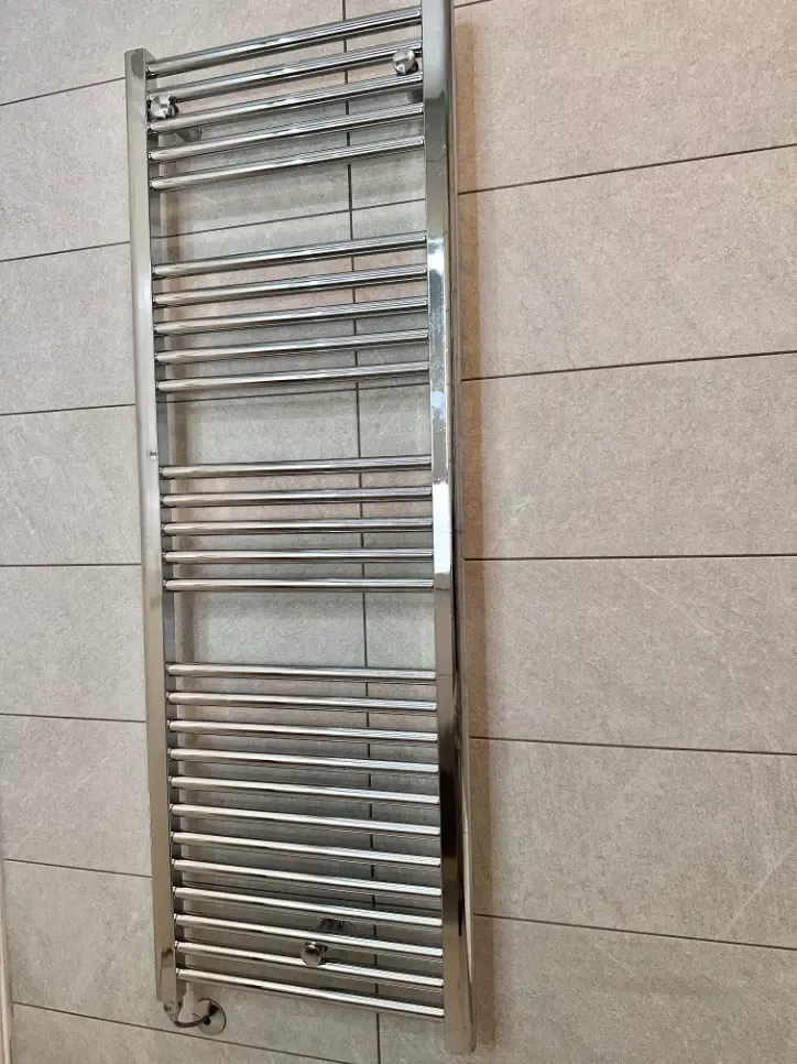 A stainless steel towel rack is hanging on a tiled wall