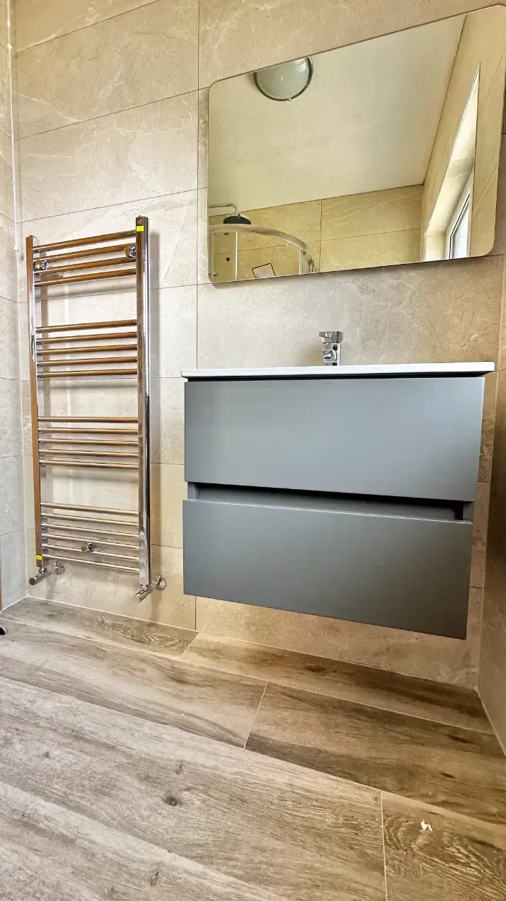 A bathroom with a sink , mirror and towel rack.