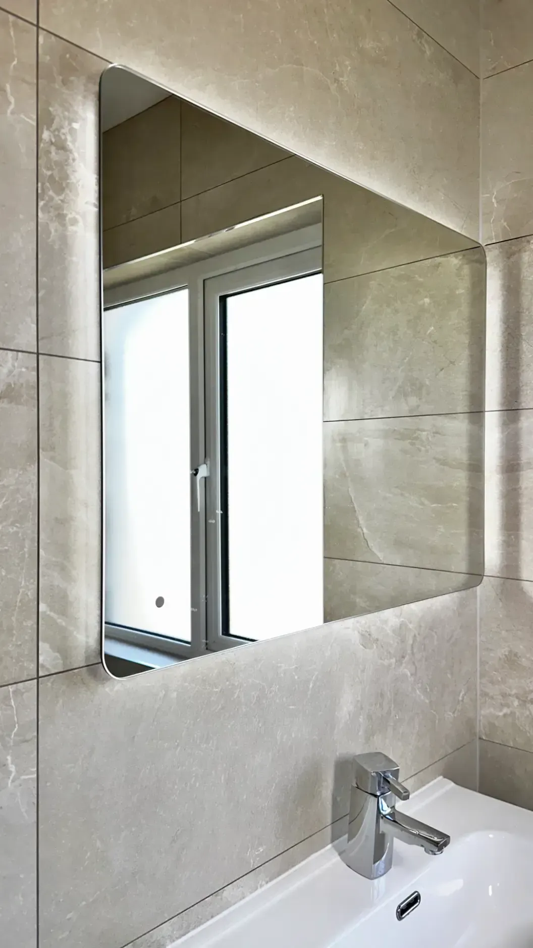 A bathroom with a sink , mirror and window.