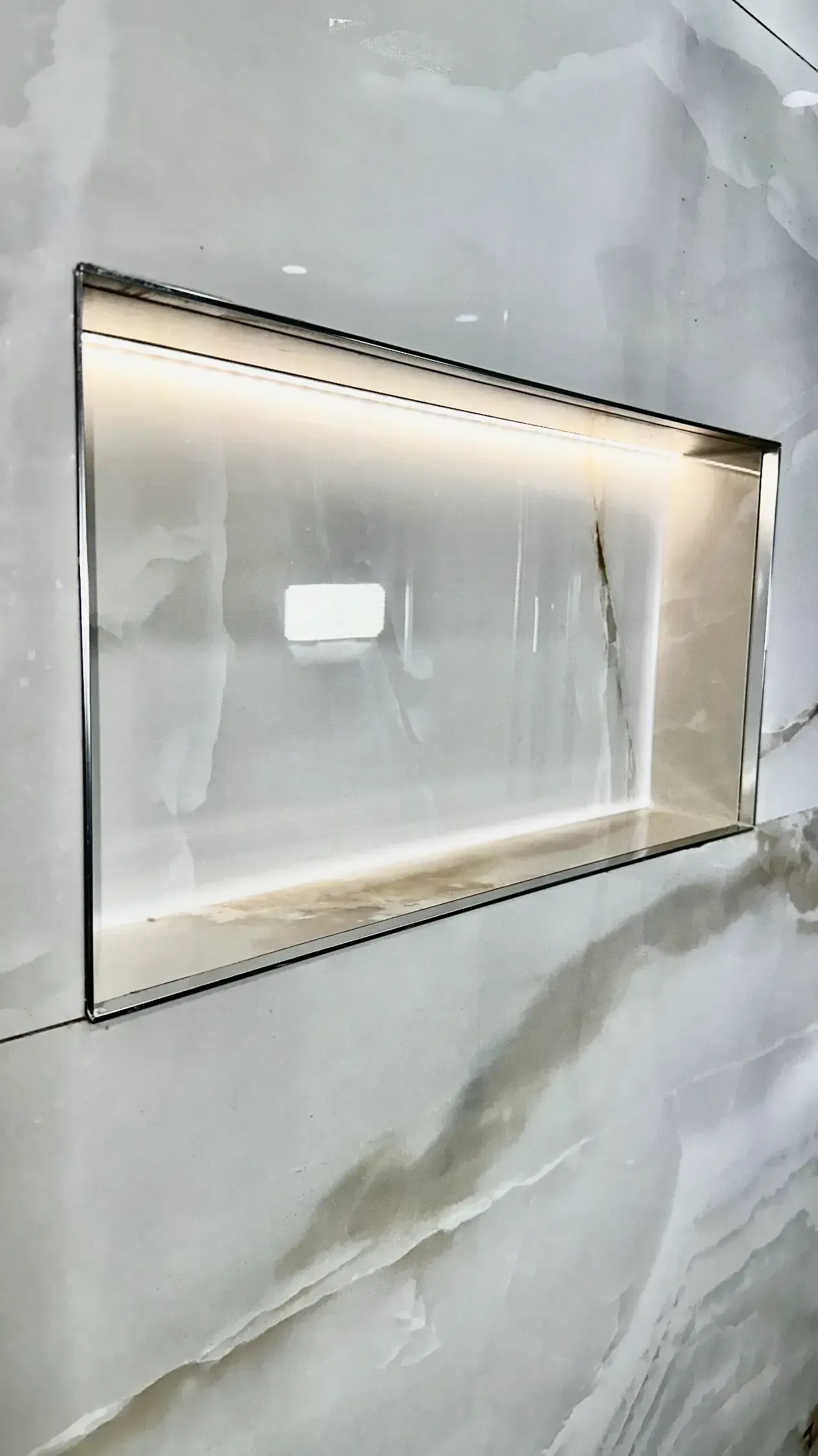 A bathroom with a shower niche and a light on the wall.